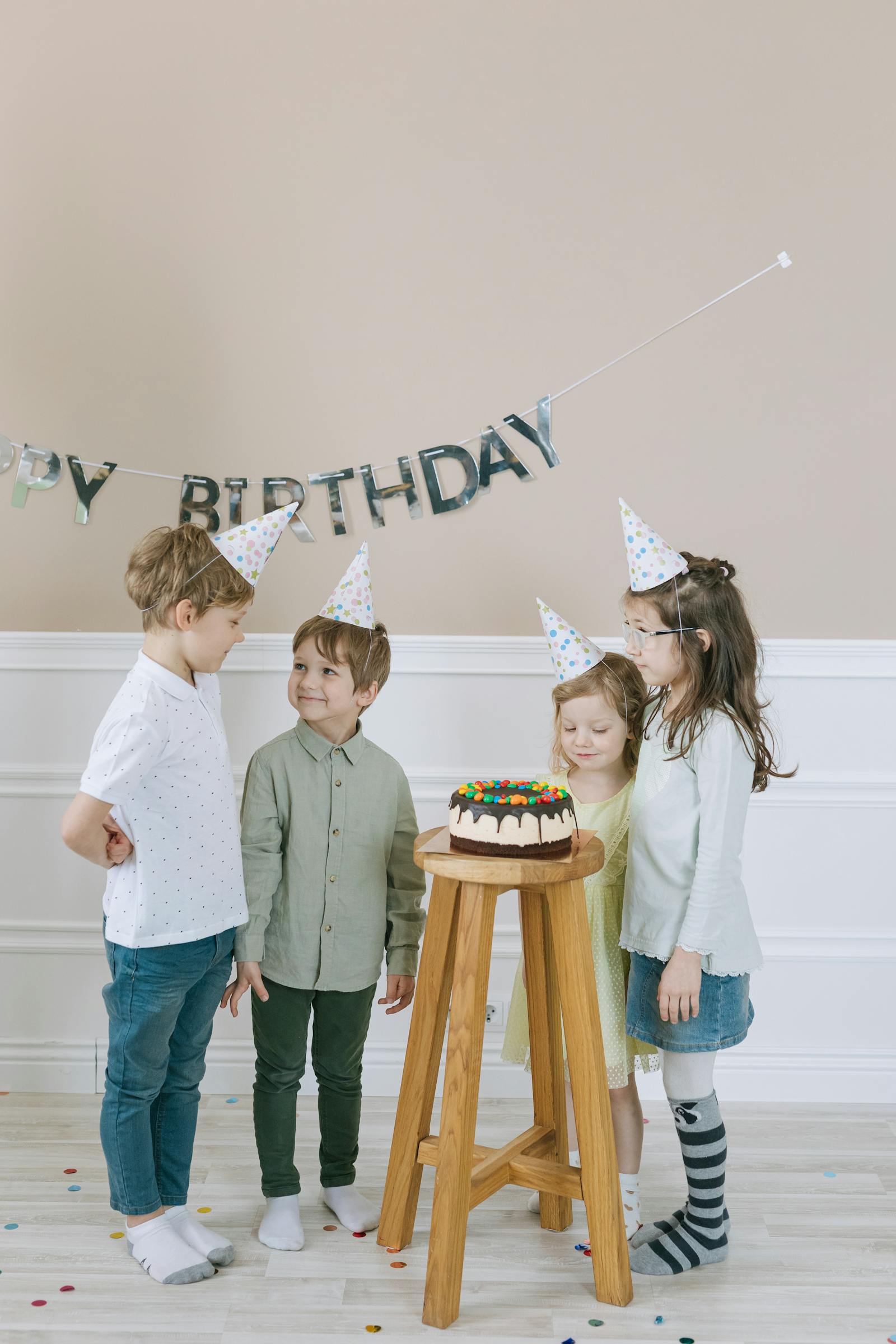أطفال حول كعكة عيد ميلاد بقبّعات احتفالية